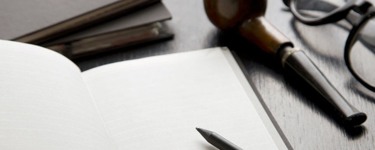 open notebook, pencil, glasses and old pipe on a desk