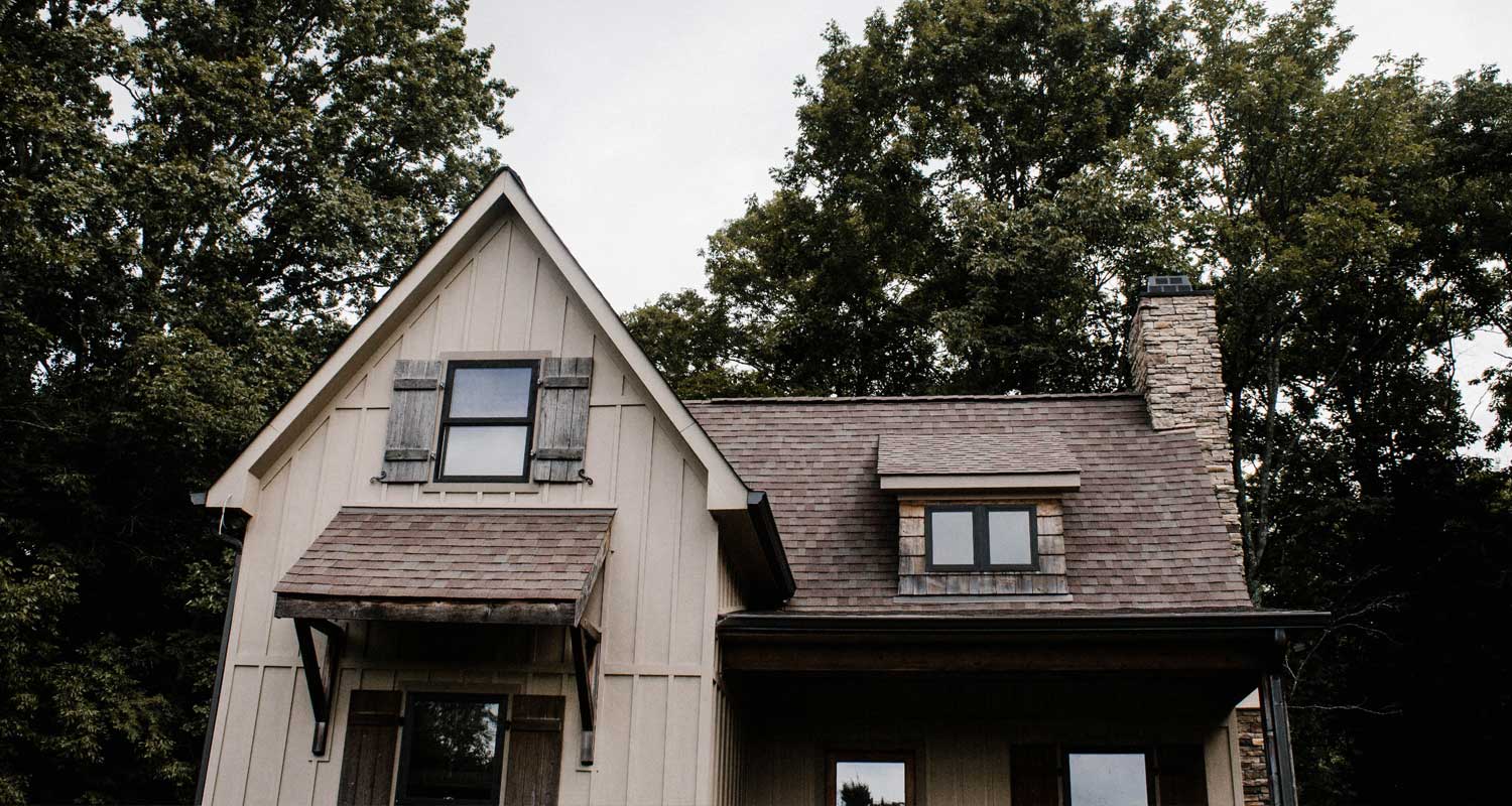 warm two story house exterior next to full grown trees